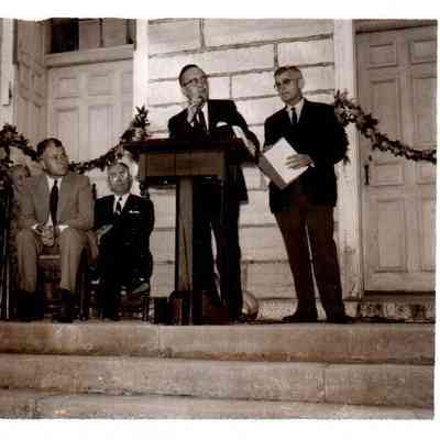 Harrodsburg Mayor J. Elmer Sims addresses a crowd. Pictured are (L to R) Judge Sam Cheek, Mrs. Mary Elizabeth Mitchell, Gov. Bert Combs, Herndon Evans, Mayor Sims, and Ralph McCallister. Mrs. Lawrence Brewer and Mrs. Floyd Wright are seated behind Mrs. Mitchell and Governor Combs. (1961)