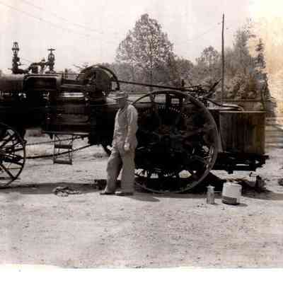 Frank Cornish stands beside the steam engine he used to thresh wheat. The machine was part of a program by the Optimist Club of which Frank was a member.