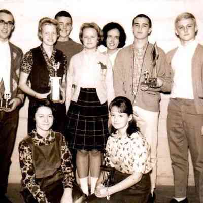 HHS Speech team brings home several trophies from an event in Paducah. Kneeling are Marilyn Graham and Joan Rue. Standing in the middle row are Allen Whitenack, Julie Keightley, Cassie James, Chris Trower, and Bill VanArsdall. The backrow has Jay Shewmaker and Mary George Shewmaker. (Dec 1963)