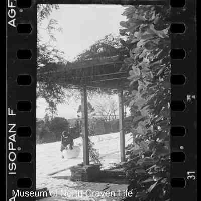 negative, sheet film - Snow Views : Child making snowman outside house (1937)