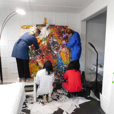 Fabiola, Elle, Abby, and Tanya removing the paper from the face of the painting. Used scissors to cut around areas that were attached to the paint itself and pulled off unattached pieces. 
