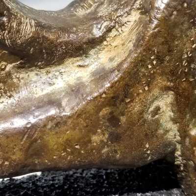 Close up: Mottled patina and patches of corrosion and scratches on surface