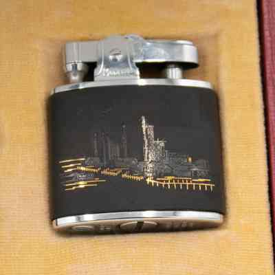 Lighter: A lighter, featuring an oil refinery scene, rests in a cushioned case.