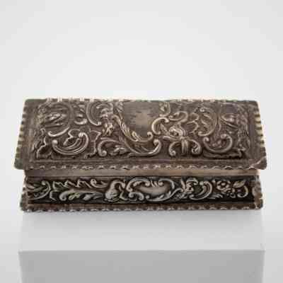 Small pressed silver-plated rectangular box.: Up close image of the small silver rectangular box embossed with a leaf swirl design
