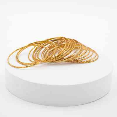 Thin gold bangles from India that belonged to Mrs. Jessie Jordan.: Image of the 19 gold bangles engraved with different geometric patterns.