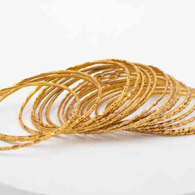 Thin gold bangles from India that belonged to Mrs. Jessie Jordan.: Image of the 19 gold bangles engraved with different geometric patterns.