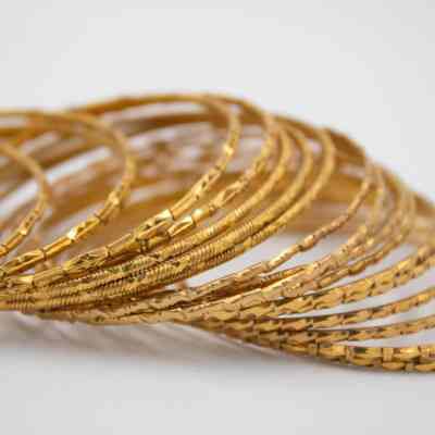 Thin gold bangles from India that belonged to Mrs. Jessie Jordan.: Up close image of 19 gold bangles engraved with different geometric patterns.