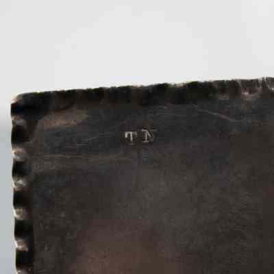 Back of the small pressed silver-plated rectangular box.: Up close image of the back of the small silver rectangular box. It is pressed with "TN."