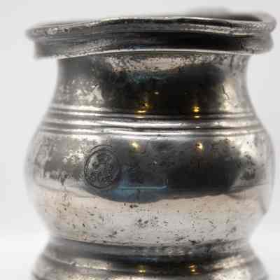 Close up of baby cup: A pewter baby cup features a crest symbolizing historical English heritage and tradition.