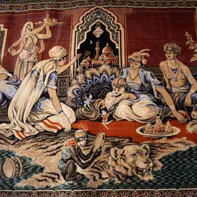 Red and blue rug: The intricate red and blue rug features a detailed harem scene, showcasing elegantly dressed figures in an exotic setting, with architectural motifs and ornate decorations.