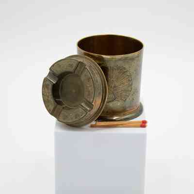 Open brass covered ashtray and match holder with blue peacock: A tall cylindrical match holder open to show the ashtray as a lid. The holder has a large peacock on the front.