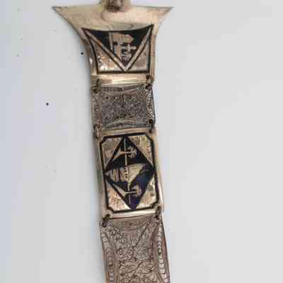 Belt: A silver belt displays intricate Iraqi scenes with beautifully detailed arabesque filigree rectangles in between. The scenes include palm trees, camels, boats, and oasis scenes.