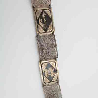 Belt: A silver belt displays intricate Iraqi scenes with beautifully detailed arabesque filigree rectangles in between. The scenes include palm trees, camels, boats, and oasis scenes.