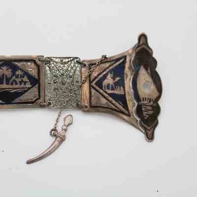 Belt clasp: The silver belt displays intricate Iraqi scenes and detailed filigree patterns. It clasps with a rounded knife-like pin.