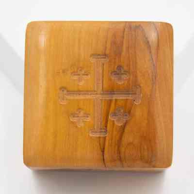 Wood rosary box: The image shows a wooden cube with an engraved cross pattern on its surface, placed against a plain background