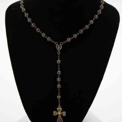 Rosary: The image shows a rosary with intricate beading, featuring a cross pendant, displayed on a black velvet stand.