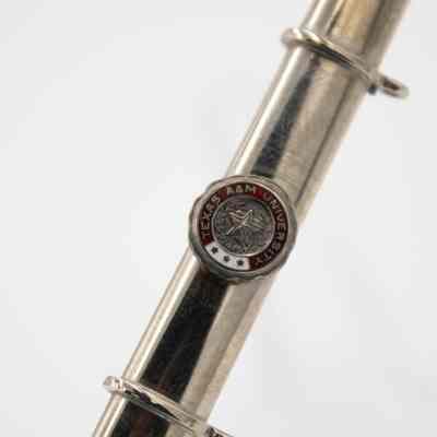 The seal on Mr. L.T. Jordan's miniature Texas A&M saber.: An up close image of the Texas A&M University seal on the saber scabbard. The seal is maroon, white, and silver with a star in the middle.