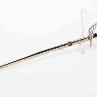 The miniature Texas A&M saber inside the scabbard: Image of the miniature Texas A&M saber sitting on a clear stand inside the scabbard.
