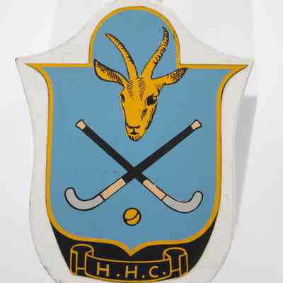 Plaque on trophy: The plaque is blue with a goat, field hockey sticks, a ball and "H.H.C" in a scroll.