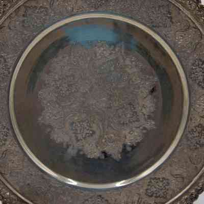 Silver plate: The silver plate is intricately engraved with a detailed and repeating ornamental pattern.