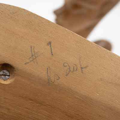 Bottom of one of the carved wooden statuettes from Africa.: Up close image of the pencil writing on the bottom of one of the carved wooden statuettes. The writing is illegible.