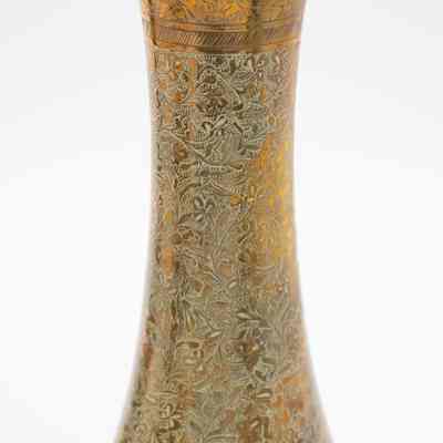 Brass vase: The image depicts a single brass fluted vase with intricate blue etched floral designs on its surface.