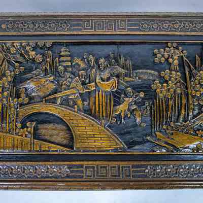 Top of coffee table: The table features intricate carvings depicting a detailed landscape scene with people, nature, and architecture.