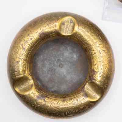 Ashtray: The image shows a round brass ashtray featuring intricate leaf designs engraved around its surface.