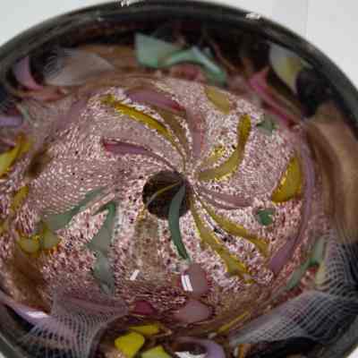 Glass ashtray: The image showcases a purple-blown glass ashtray adorned with vibrant, swirling patterns of colors.