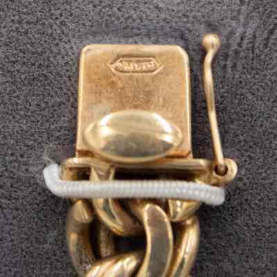 Clasp and chain: The gold bracelet has a clasp stamped with illegible words, and a doubled chain.