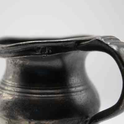 Back of pewter baby cup: A close-up of an antique pewter baby cup with distinct curved handle.