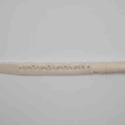 Thin carved ivory letter opener with elephants on the blade.: Image of the thin carved ivory letter opener. There are elephants carved into the blade and leaves around the base.