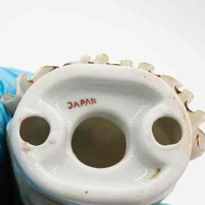 Bottom of the painted porcelain figurine of a girl.: Up close image of the bottom of the porcelain figurine of a girl. It is stamped with "JAPAN" in red print.