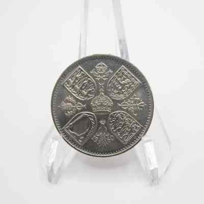Back of five shilling coin: The back of a Queen Elizabeth II five shilling coin features a detailed design with a royal crown at the center, surrounded by four shields.