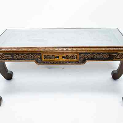 Coffee table: The carved wood coffee table features intricate detailing and elegantly arched legs, topped with glass.