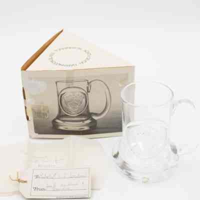 Side of triangle box, Dartington Glass tankard, and notes.: Image of the glass tankard pressed with King Edgar's head. There is a small sticker on the bottom that says "Dartington England." Two notes found with the tankard. The card reads "To: Mr. + Mrs. L.T. Jordan" and "From: Jack, Nadine, + Deirdre." The tissue paper reads "To Jessie with love from Deirdre." The side of the box shows an image of the tankard.