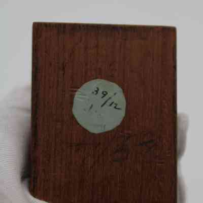 Bottom of wooden pedestal: The bottom of the wooden pedestal has a gray circle and many handwritten numbers.
