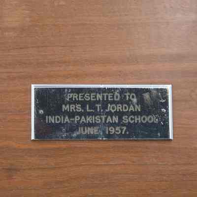 Plaque on the footed carved wooden tray from the India-Pakistan School.: Up close image of the silver plaque on the footed carved wooden tray. The plaque is engraved with "PRESENTED TO MRS. L.T. JORDAN INDIA-PAKISTAN JUNE 1957."