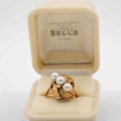 Gold knotted ring that belonged to Mrs. Jessie Jordan.: Up close image of the ring with a knotted gold design and three pearls in a diagonal in a white case.