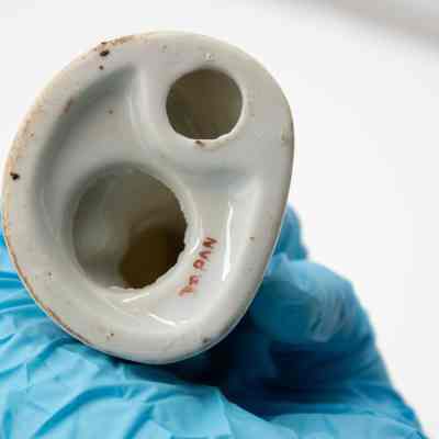 Bottom of the painted porcelain figurine of a boy.: Up close image of the bottom of the porcelain figurine of a boy. It is stamped with "JAPAN" in red print.