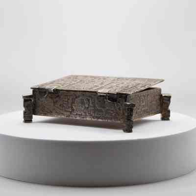 Cigarette box: The silver cigarette box showcases intricate Incan-style mythological art, featuring detailed chased coin designs.