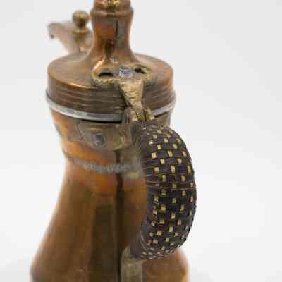 Coffee pot handle: A copper coffee pot features a woven leather handle and stamped Arabic script detailing.
