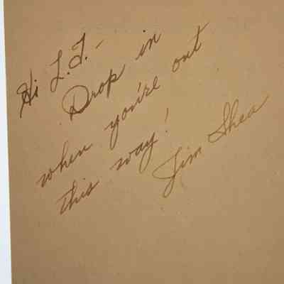 Back of Letter: Close-up image of the letter's back where writing in dark ink can be found. The writing reads "Hi L.T. - Drop in when you're out this way! Jim Shea."