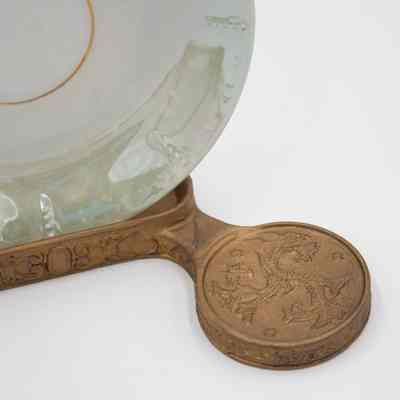 Details on stand: The image shows a celadon green saucer resting in an ornate gold-toned stand, exquisitely designed.
