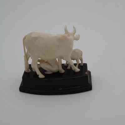 Back view of ivory figure of a child milking a cow: The ivory figure depicts a child milking a cow, viewed from the back.