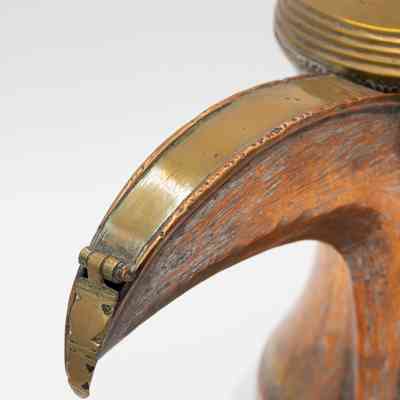 Spout on coffee pot: The image shows a detailed view of a large brass coffee pot featuring a curved spout with a hinged design.