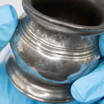 Close up of baby cup: A pewter baby cup features a crest symbolizing historical English heritage and tradition.