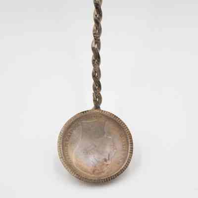 Front of 1932 Bolivar Spoon: Closeup of the spoons bowl. It is the front of the coin, upside down with a side profile of Simon Bolivar. It says "Liberator Bolivar" around his profile.
