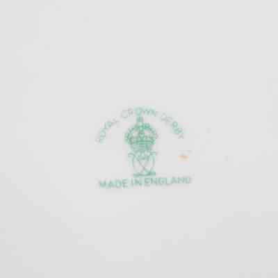 Back of Royal Crown Derby dish presented to Mrs. Jessie Jordan at the Twelfth Annual Ladies' Festival at the Kuwait Masonic Lodge on February 15, 1961.: Up close image of the maker's mark stamp on the back of the bone China dish. It is stamped in green ink and reads "ROYAL CROWN DERBY MADE IN ENGLAND" with a royal crown and other symbol included.
