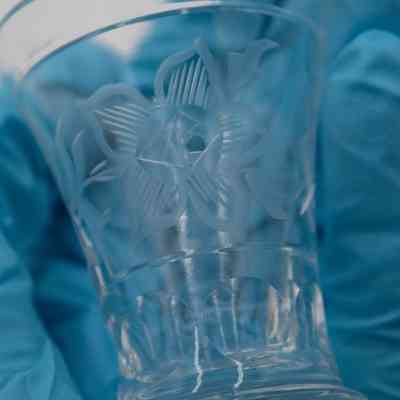 Small glass: A clear glass is delicately etched with intricate floral designs on its surface.